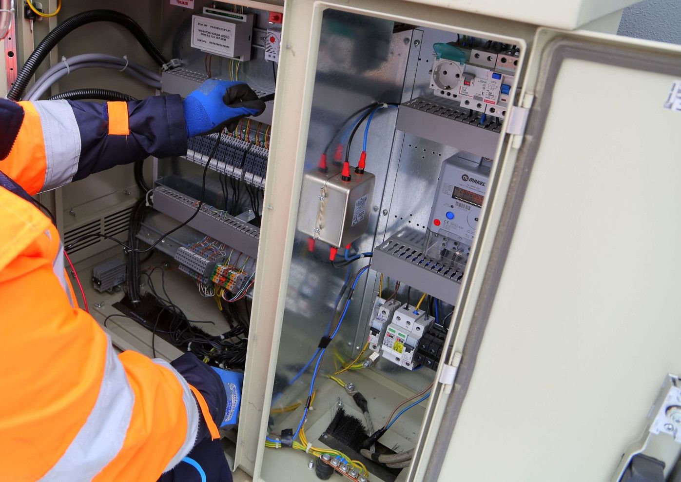 Engineer in safety gear working on an outdoor electrical panel, ensuring system functionality.
